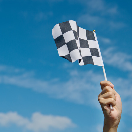 checkered race flag in hand.の写真素材