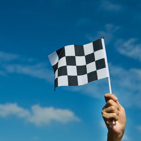 checkered race flag in hand.の写真素材