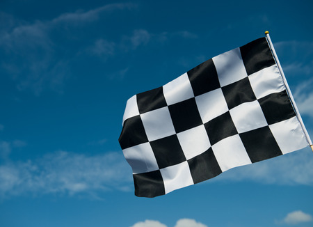 checkered race flag waving on blue sky.の写真素材