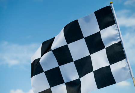 checkered race flag waving on blue sky.の写真素材
