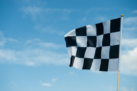 checkered race flag waving on blue sky.の写真素材