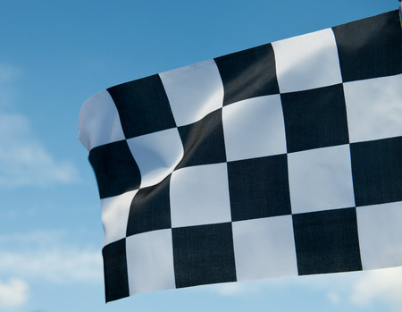 checkered race flag waving on blue sky.の写真素材