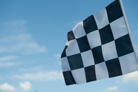 checkered race flag waving on blue sky.の写真素材