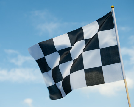 checkered race flag waving on blue sky.の写真素材