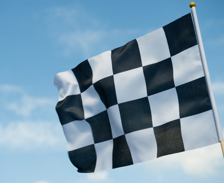 checkered race flag waving on blue sky.の写真素材