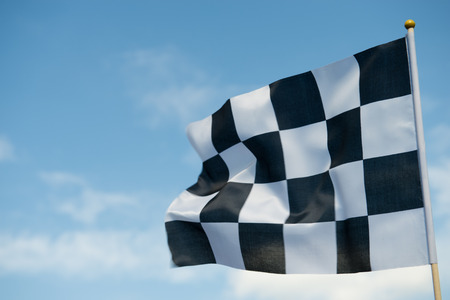 checkered race flag waving on blue sky.の写真素材
