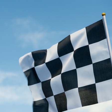 checkered race flag waving on blue sky.の写真素材