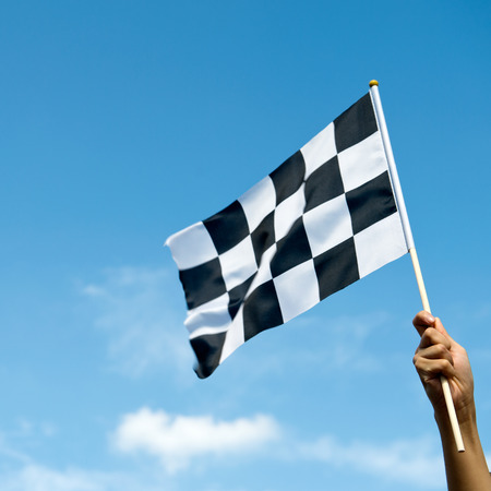 checkered race flag in hand.の写真素材
