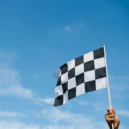 checkered race flag in hand.の写真素材
