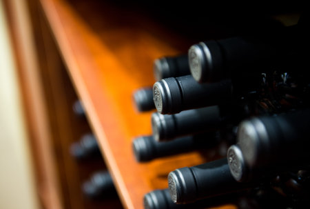 Group of red wine bottles stacked on wooden racks.