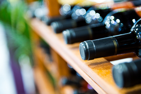 Group of red wine bottles stacked on wooden racks.の写真素材