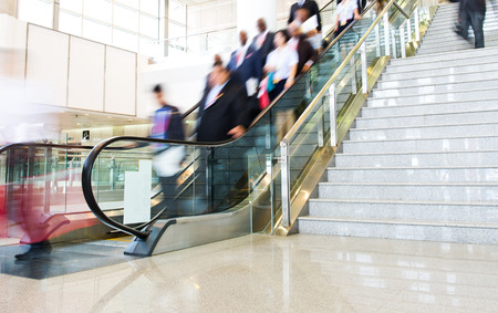 Group of businesspeople moving down on escalator in office. blurred motion.のeditorial素材