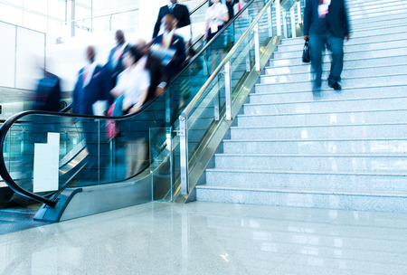 Group of businesspeople moving down on escalator in office. blurred motion.のeditorial素材