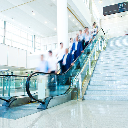 Group of businesspeople moving down on escalator in office. blurred motion.のeditorial素材