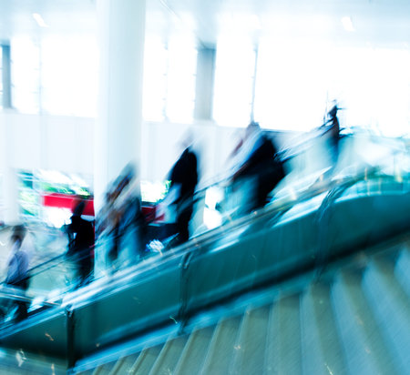 Group of businesspeople moving down on escalator in office. blurred motion.の写真素材
