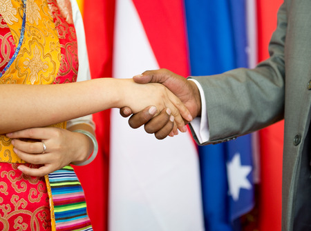 African businessman's hand shaking white Chinese woman's hand.の写真素材