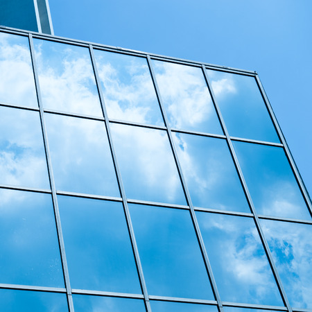 Sky and clouds reflected in windows of modern office building.の写真素材
