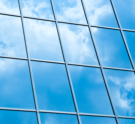 Sky and clouds reflected in windows of modern office building.の写真素材