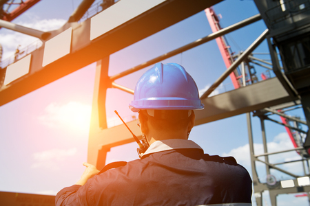 engineer in hard-hat overlooking large commercial container port.の写真素材