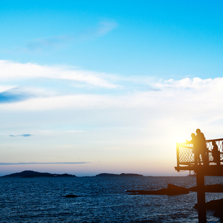 Man and woman enjoying the sea together at sunset.の写真素材