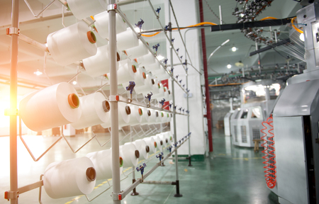 Textile industry - yarn spools on spinning machine in a textile factoryの写真素材