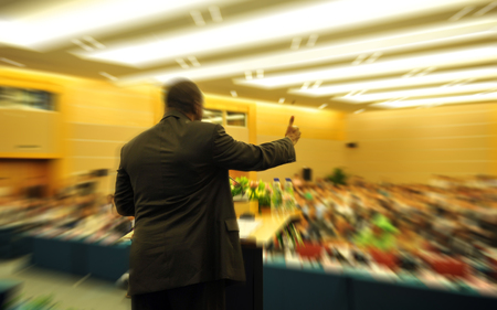 Business man is making a speech in front of a big audience at a conference hall.の写真素材
