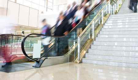 Group of businesspeople moving down on escalator in office. blurred motion.のeditorial素材