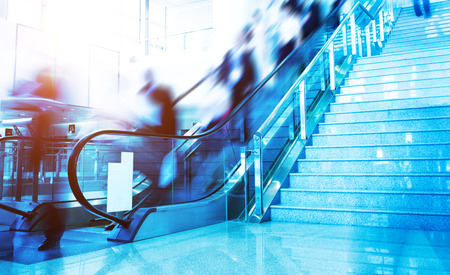 Group of businesspeople moving down on escalator in office. blurred motion.のeditorial素材
