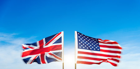 USA and Britain flags against blue sky backgroundの写真素材