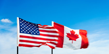 USA and Canada flags against blue sky backgroundの写真素材