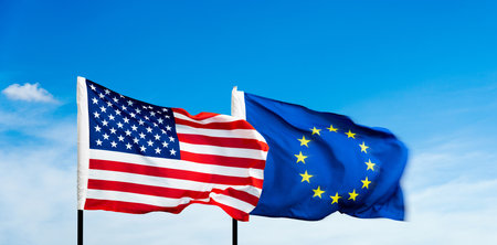 USA and European Union flags against blue sky backgroundの写真素材