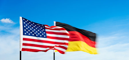 USA and German flags against blue sky backgroundの写真素材
