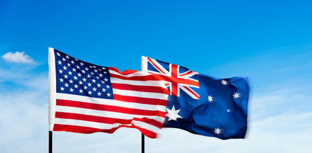 USA and Australia flags against blue sky backgroundの写真素材