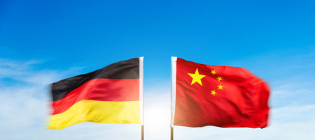 China and German flags against blue sky backgroundの写真素材