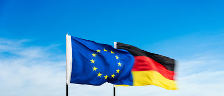 German and European Union flags against blue sky backgroundの写真素材