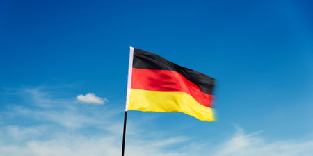 German flag waving against blue sky backgroundの写真素材