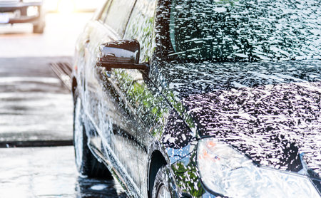 Washing car with flowing water and foamの写真素材