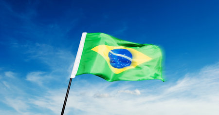 Brazilian flag waving against blue sky backgroundの写真素材