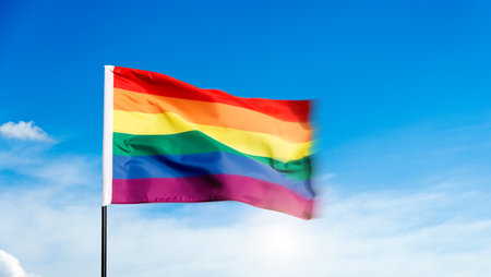 Rainbow flag waving on blue skyの写真素材