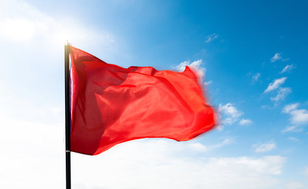 Red flag waving on blue skyの写真素材
