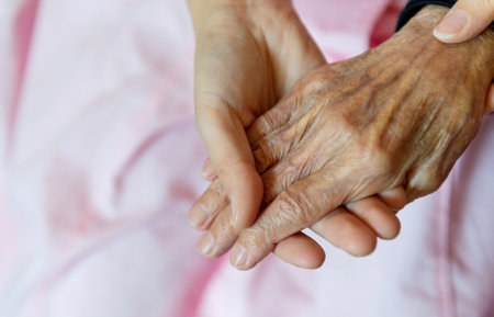 Young girl's hand holding old woman's wrinkled handsの写真素材