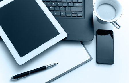 Modern workplace with digital tablet, laptop, pen and papersの写真素材