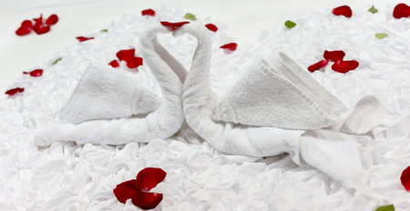 Two swans and heart made from towels on honeymoon bedの写真素材