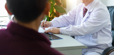 Doctor and patient talking and discussing health treatment while sitting at the deskの写真素材
