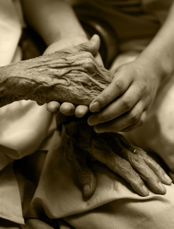 Young girl's hand holding old woman's wrinkled handsの写真素材