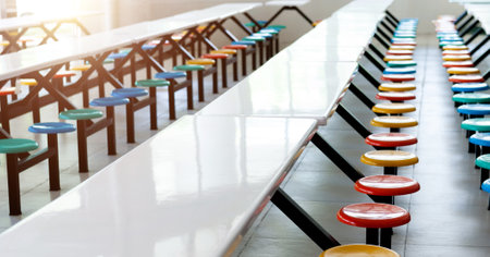 Clean school cafeteria with white tables and colorful seatsの写真素材