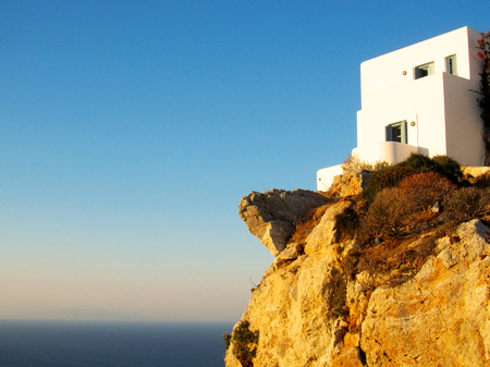 A traditional white Greek house on a rock rising straight from the seaのeditorial素材