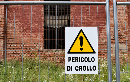 A yellow warning of danger to collapse in front of one buildings of the old damaged Cittadella of Alessandria, Italy.の写真素材