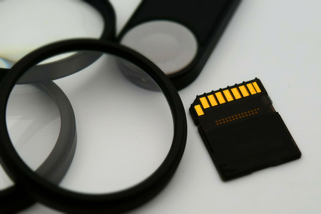 Concept for modern digital photography tools: lens filter, memory card and remote control. On white background and tilt-shift effect applied.の写真素材