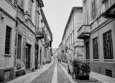 An almost empty street in Cremona in Italy with houses and buildings. Black and white.のeditorial素材